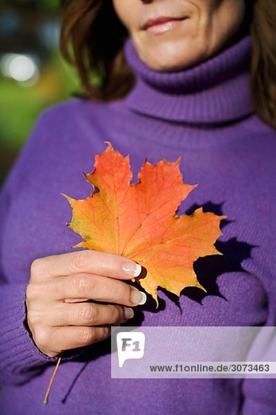 A woman holding an autumn leaf Sweden.