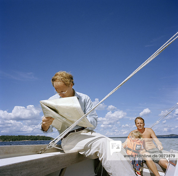 Zwei Männer und ein Kind auf einem Segelboot Schweden.