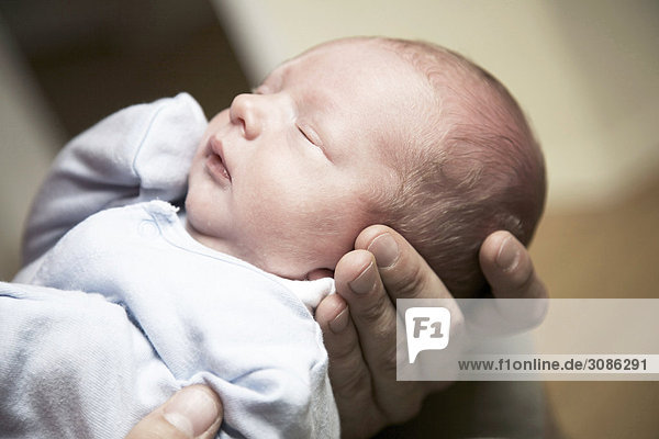 Mann hält schlafendes Baby in den Händen  Close-up