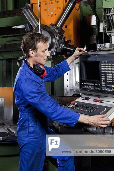 A man operating a machine in a metal parts factory