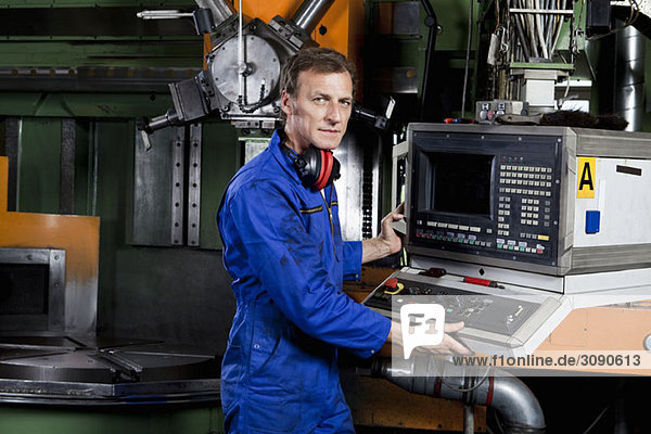 Ein Mann  der eine Maschine in einer Metallteilefabrik bedient.