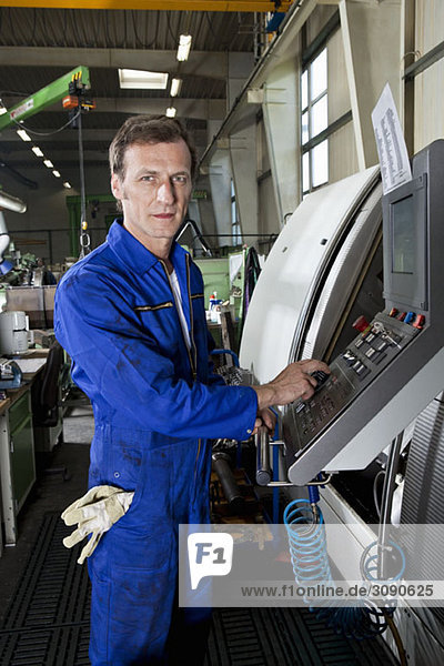 Ein Mann  der eine Maschine in einer Fabrik bedient.
