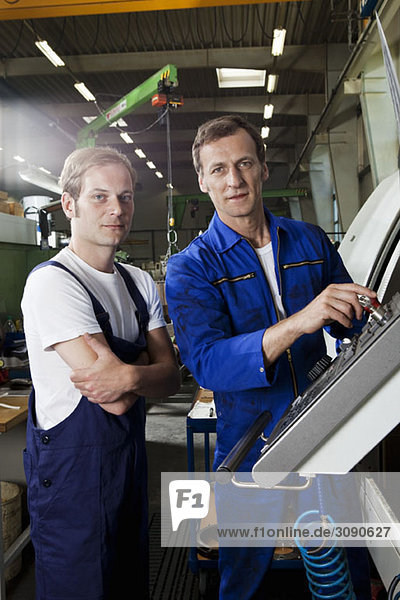 Two manual workers in a metal parts factory