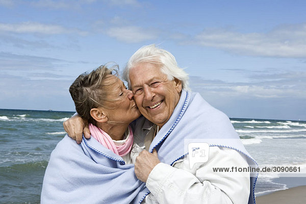 Ein älteres Paar  das zusammen am Strand spazieren geht.