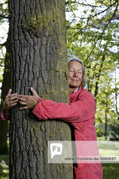A senior woman hugging a tree