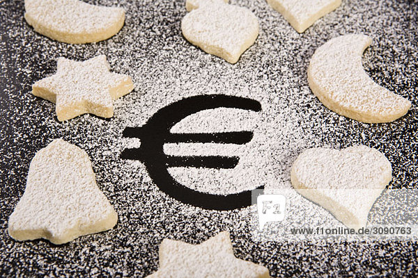 Das Euro-Symbol in Puderzucker umgeben von verschiedenen Gebäckformen