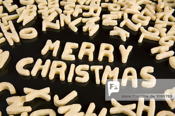 Buchstabenkekse  die den Satz Frohe Weihnachten buchstabieren.
