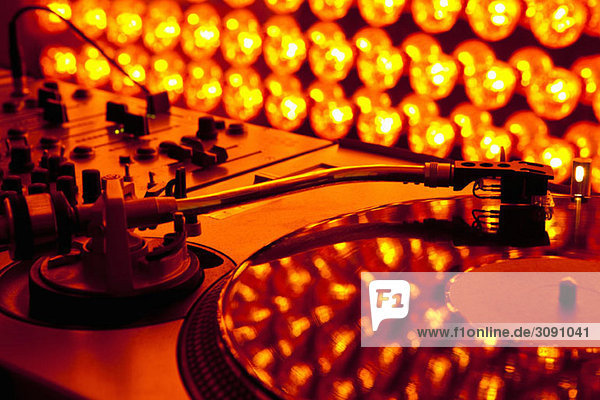 A turntable and sound mixer illuminated by lighting equipment