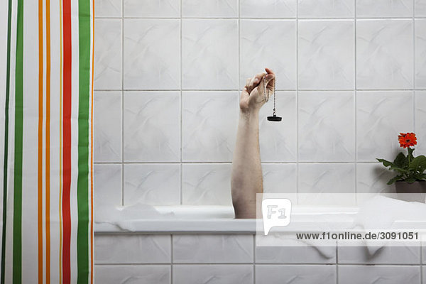 A human hand sticking out of a bathtub holding a bath plug