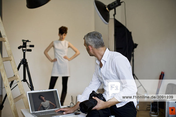 Ein Fotograf mit einem Laptop am Set eines Modeshootings