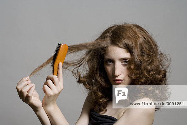 Eine junge Frau  die sich die Haare bürstet.