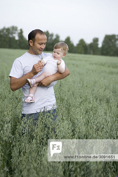 A father carrying his baby daughter in a field