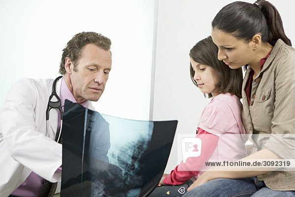 Ein männlicher Arzt  der den Patienten ein Röntgenbild zeigt.