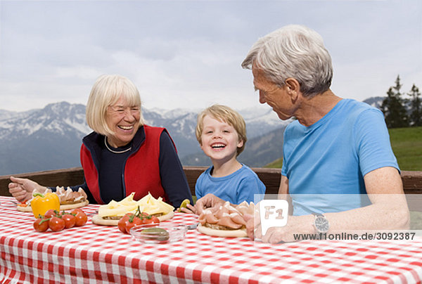 Paar und Enkel beim Essen in den Bergen