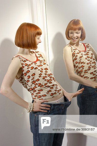 Frau betrachtet Gewichtsabnahme im Spiegel