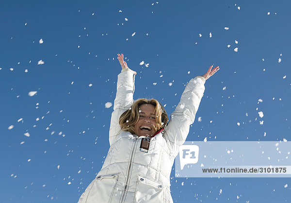 Seniorin wirft lachend Schnee in die Luft