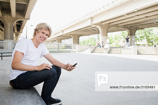 Jugendlicher Junge mit Handy im Skatepark