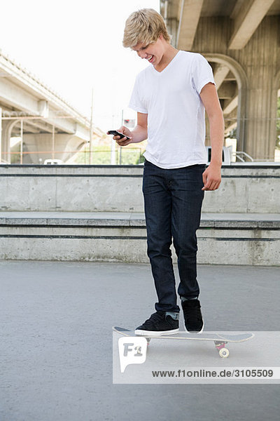 Teenager Junge auf Skateboard mit Handy