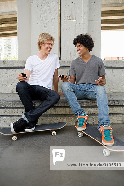 Teenage boys with cellphones and skateboards