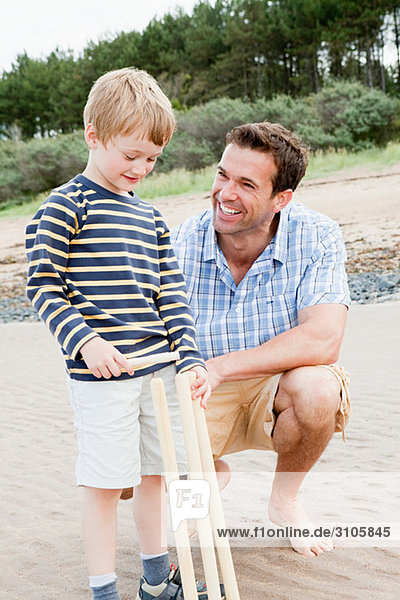 Vater und Sohn am Strand mit Kricketstümpfen