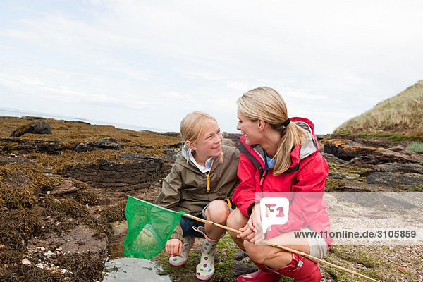 Mother and daughter by rock pools