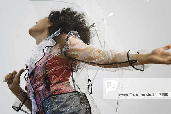 Junge Frau in klarem Plastik-Regenmantel im Regen stehend  Blickwinkel niedrig