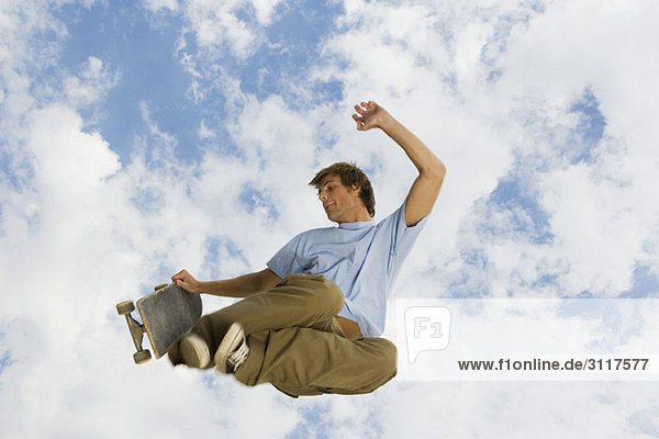 Junger Mann mit Skateboard in der Luft
