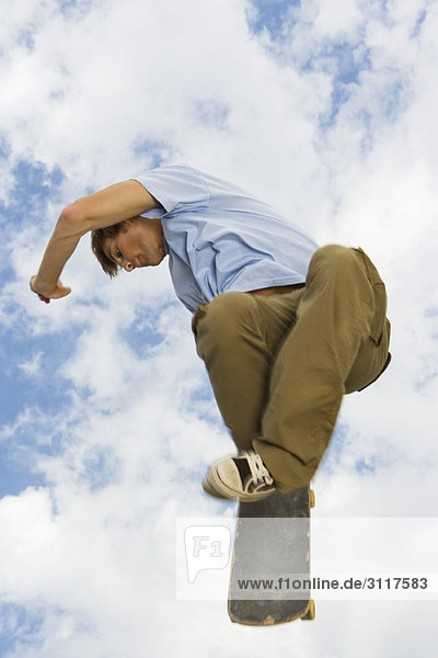 Junger Mann mit Skateboard-Trick in der Luft
