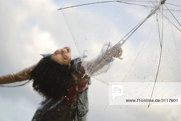 Junge Frau hält Schirm hoch  lächelt vor der Kamera