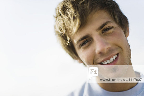 Young man smiling at camera with head tilted  portrait