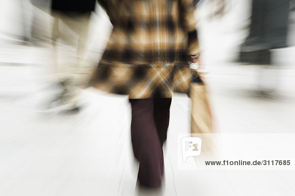 Shopper Walking mit Einkaufstasche in der Hand  Rückansicht  beschnitten