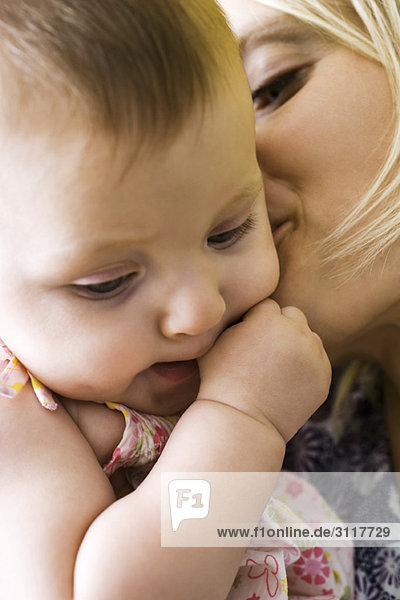 Mother kissing infant's cheek  close-up