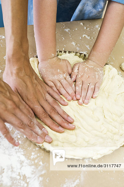 Mutter und Kind machen zusammen Kuchenkruste  Ausschnittdarstellung