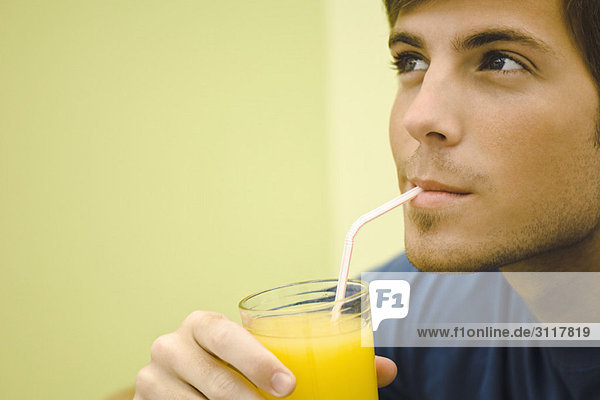 Junger Mann trinkt Orangensaft