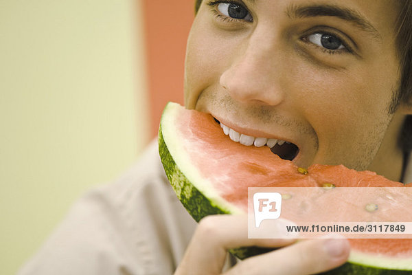 Junger Mann isst Wassermelonenscheibe