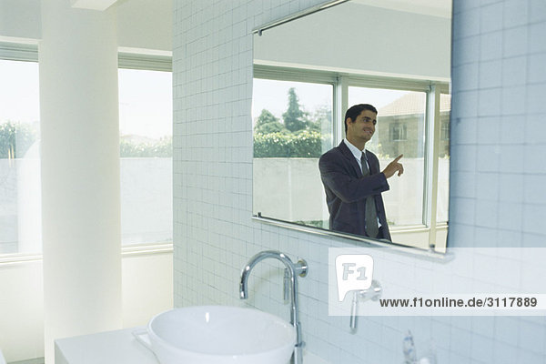 Businessman in bathroom having conversation with person out of frame