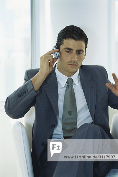 Businessman sitting with legs crossed using cell phone