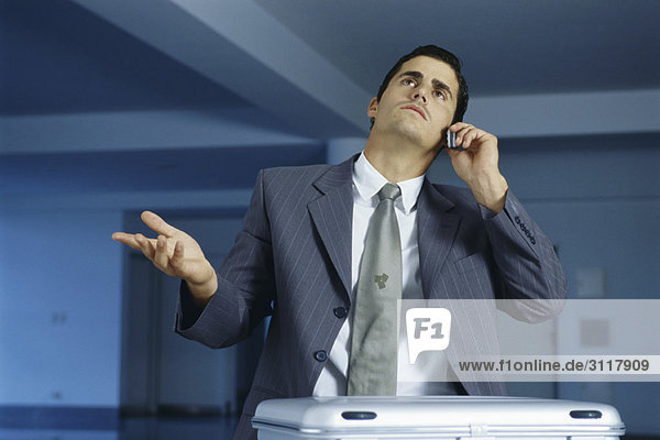 Businessman talking on cell phone  making frustrated gesture with hand