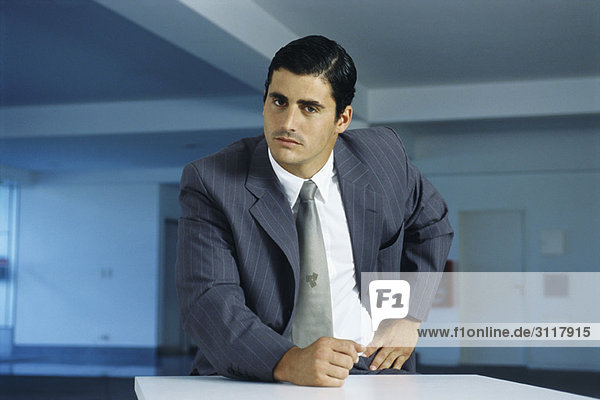 Businessman staring intently at camera with clenched fist on table