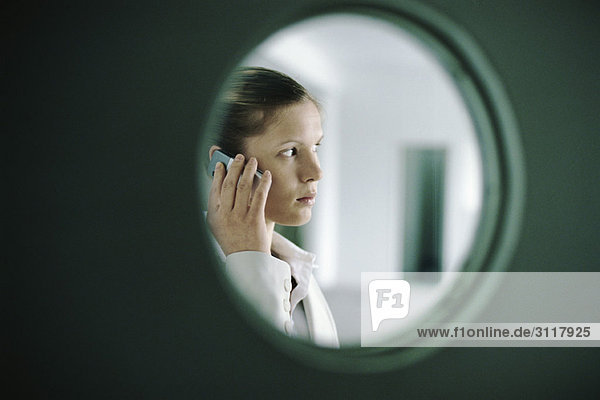 Woman using cell phone  viewed through window
