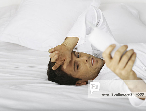 Man lying in bed  dialing cordless phone