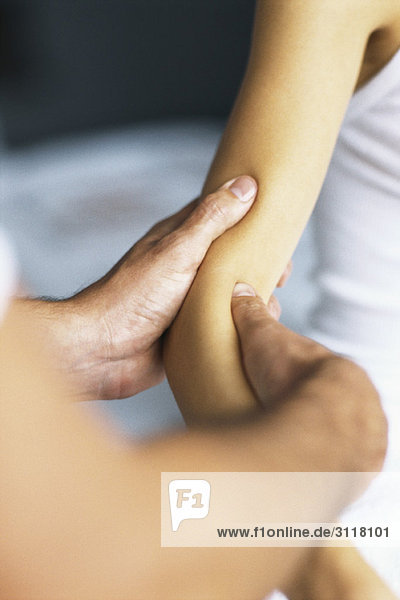 Massagetherapeutin  die den Arm des Patienten massiert.