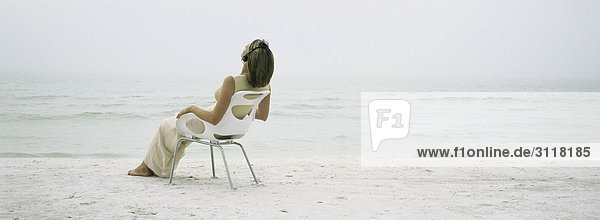 Frau entspannt sich im Sessel am Strand