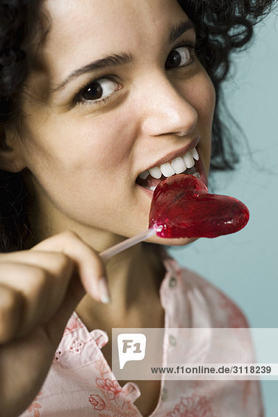 Junge Frau isst herzförmigen Lolli