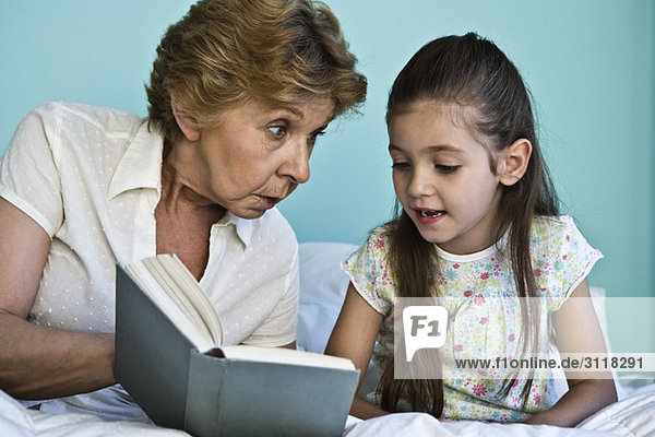 Kleines Mädchen liest Buch mit Großmutter