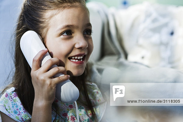 Little girl smiling using landline phone