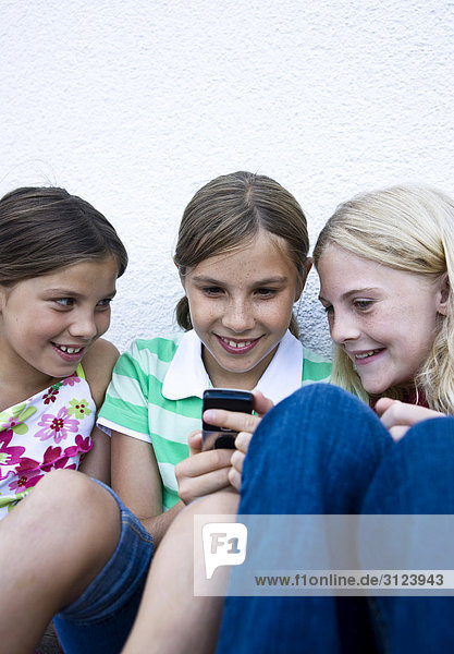 Drei Mädchen schauen auf ein Handy