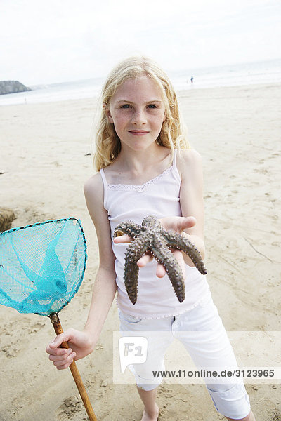 Girl holding a starfish into the camera
