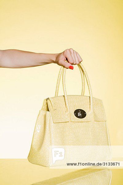 Frau hält gelbe Handtasche