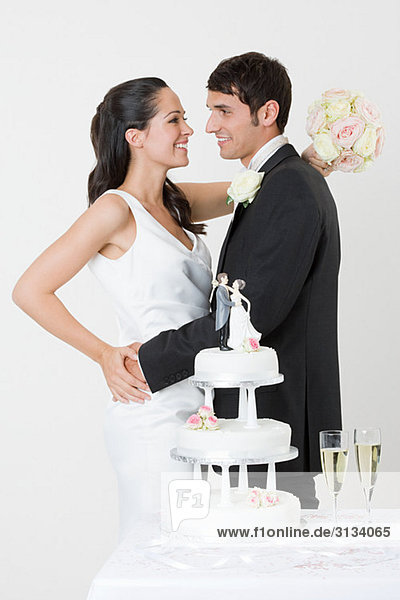 Newlyweds standing near wedding cake